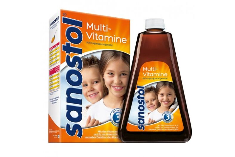 Verpackung von Sanostol Multivitaminen mit einem Fläschchen und einer Schachtel, abgebildete Kinder lächeln.