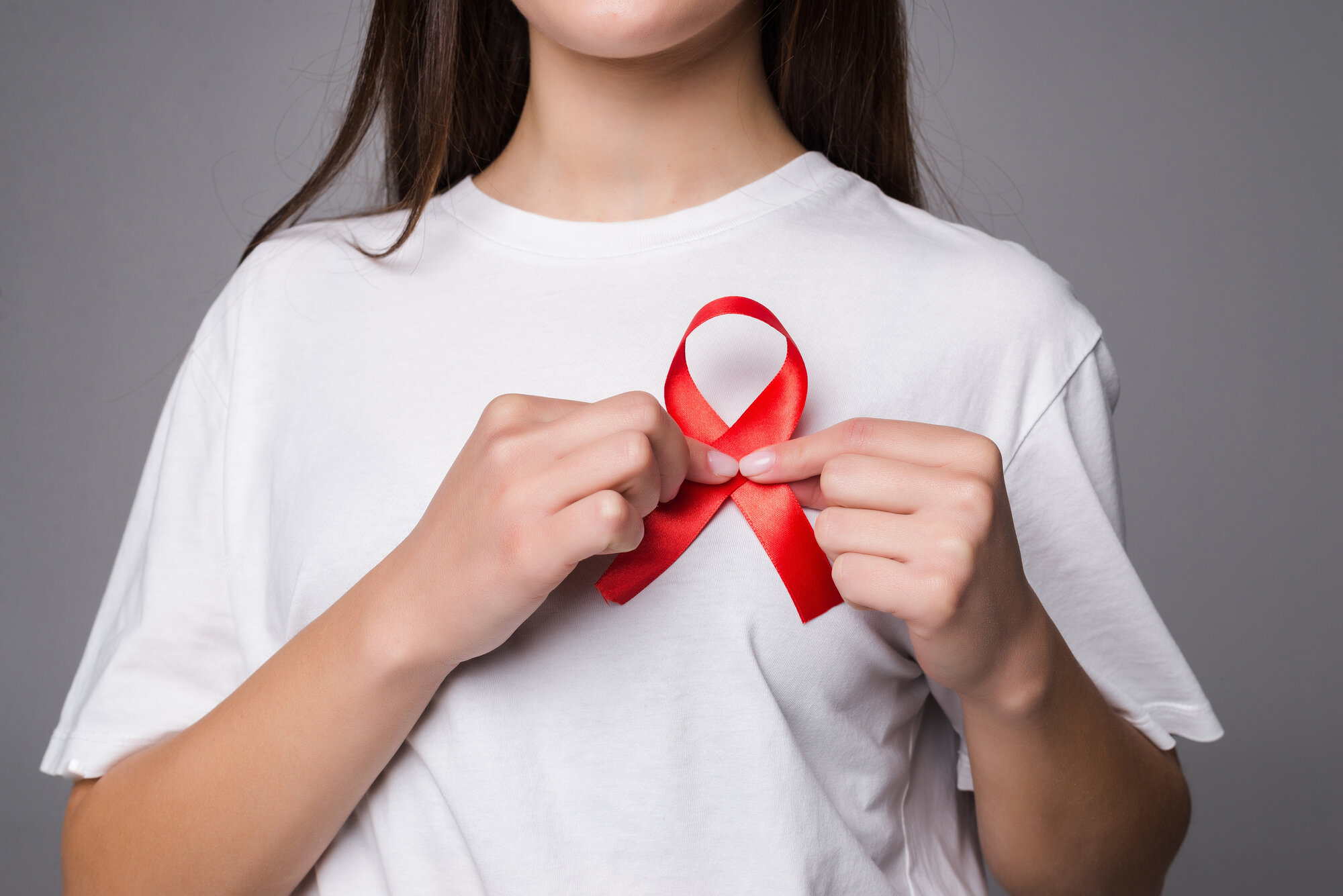 woman-holding-breast-with-pink-ribbon-white-wall-concept-photo-support-breast-cancer-cause-ps-you-can-change-pink-ribbon-into-red-aids-support-cause.jpg